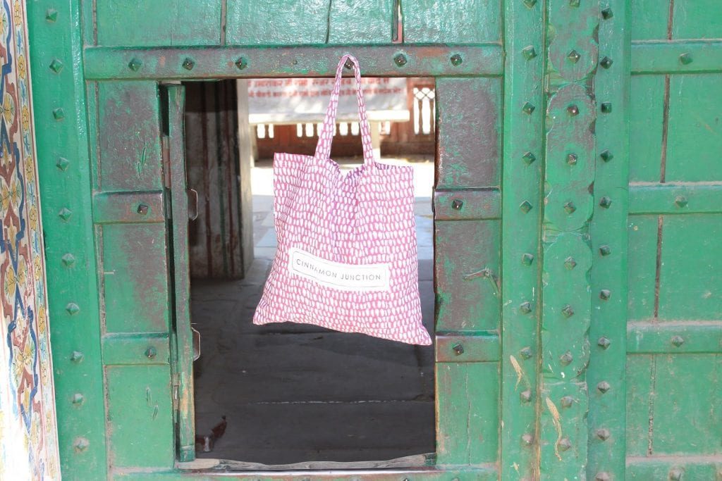 raspberry monsoon duvet set bag hanging from a green painted door