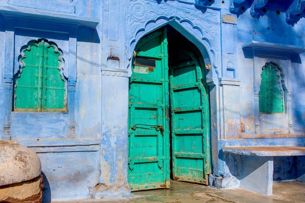 Green door in a Jodhpur building with indigo blue walls